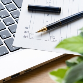 ノートパソコンと履歴書の画像