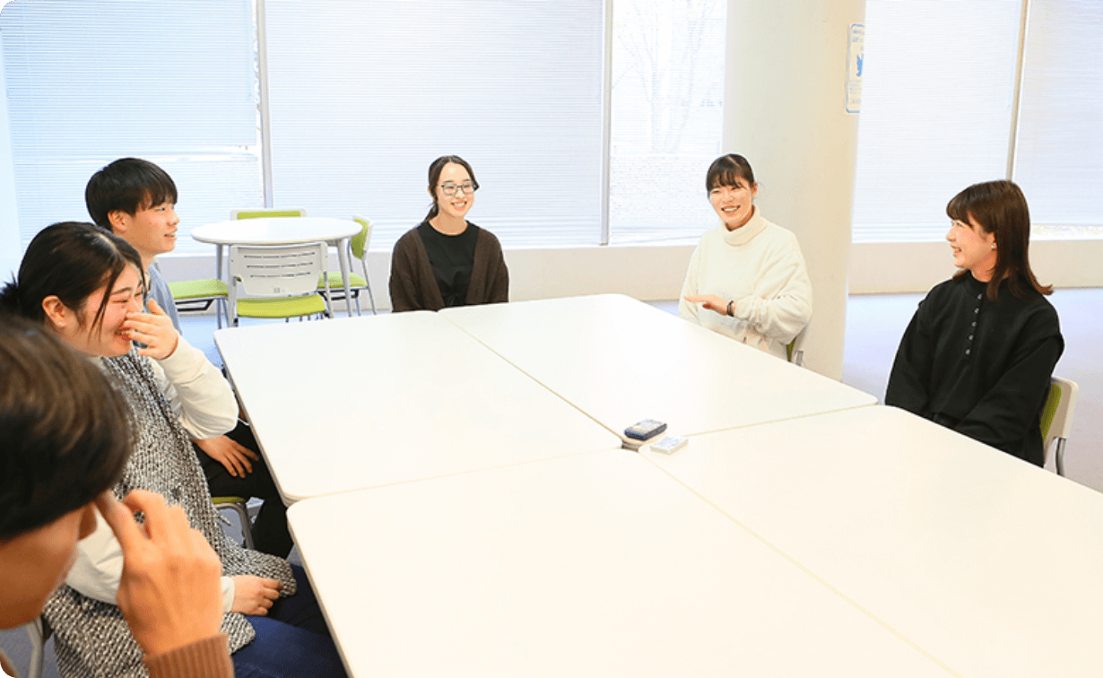 机を挟んで談笑する学生たちの様子