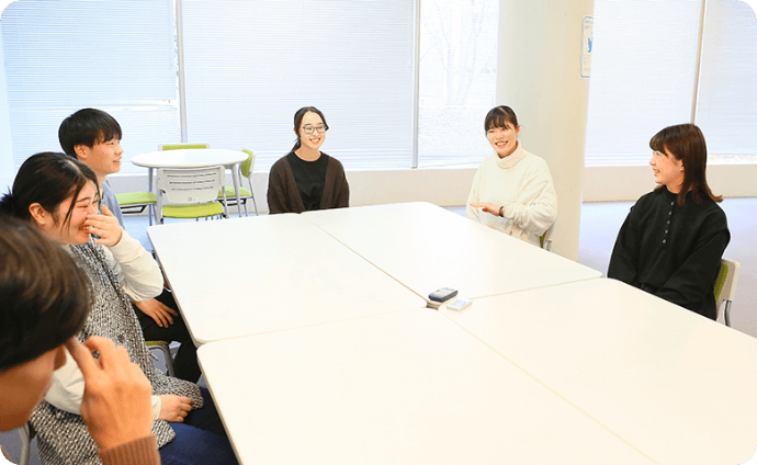 机を挟んで談笑する学生たちの様子