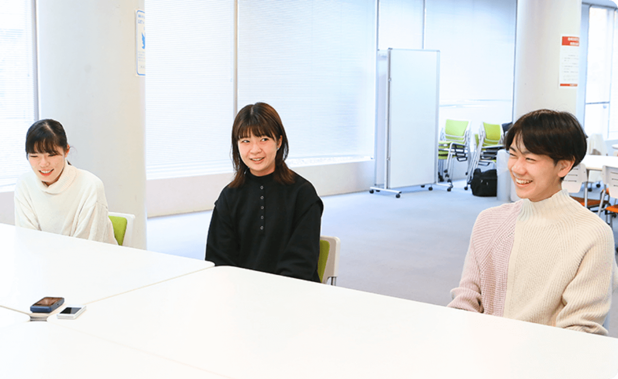 机を挟んで談笑する学生たちの様子