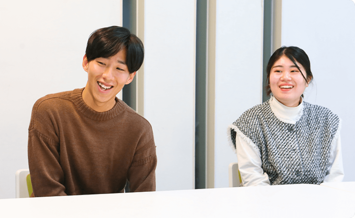 机を挟んで談笑する学生たちの様子