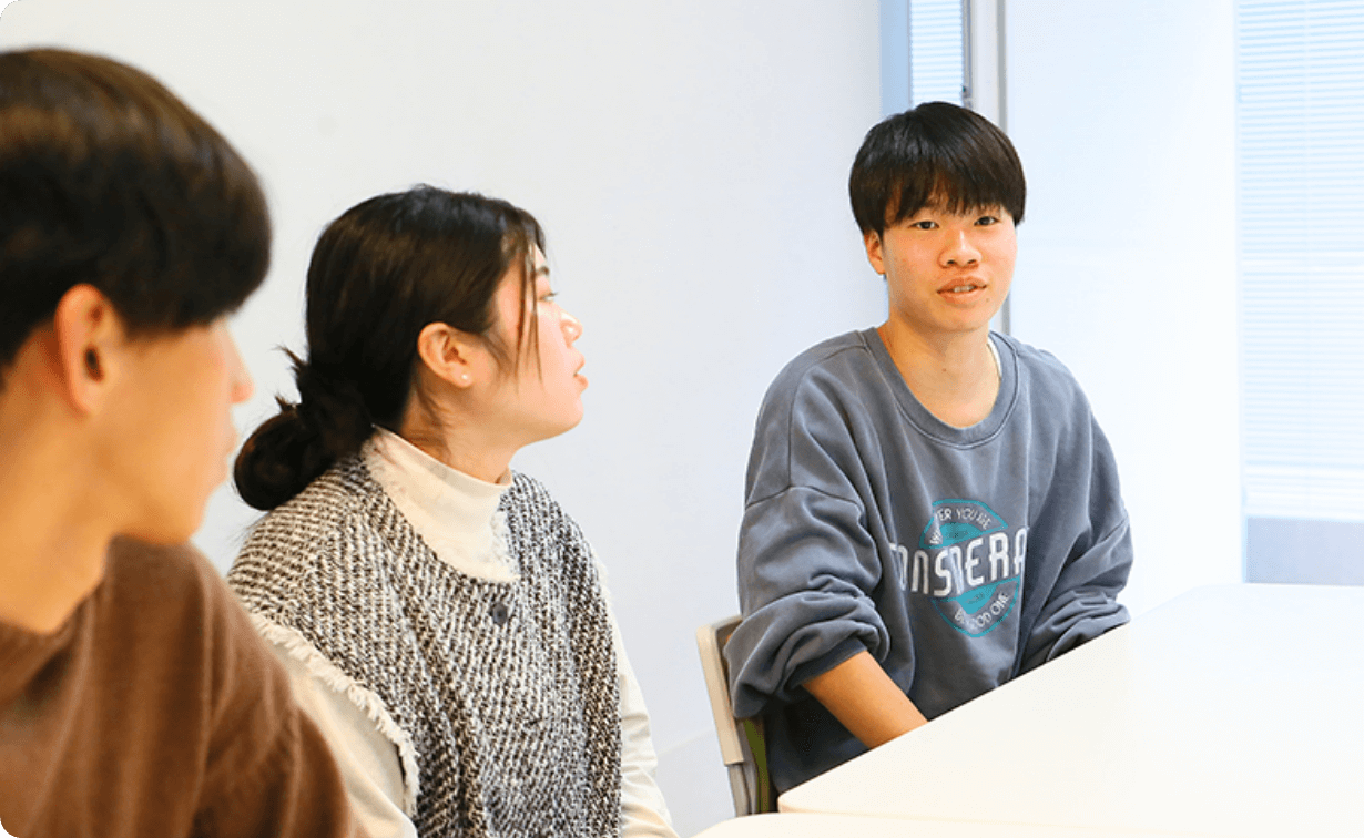 机を挟んで談笑する学生たちの様子