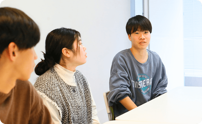 机を挟んで談笑する学生たちの様子