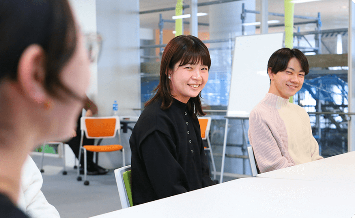 机を挟んで談笑する学生たちの様子