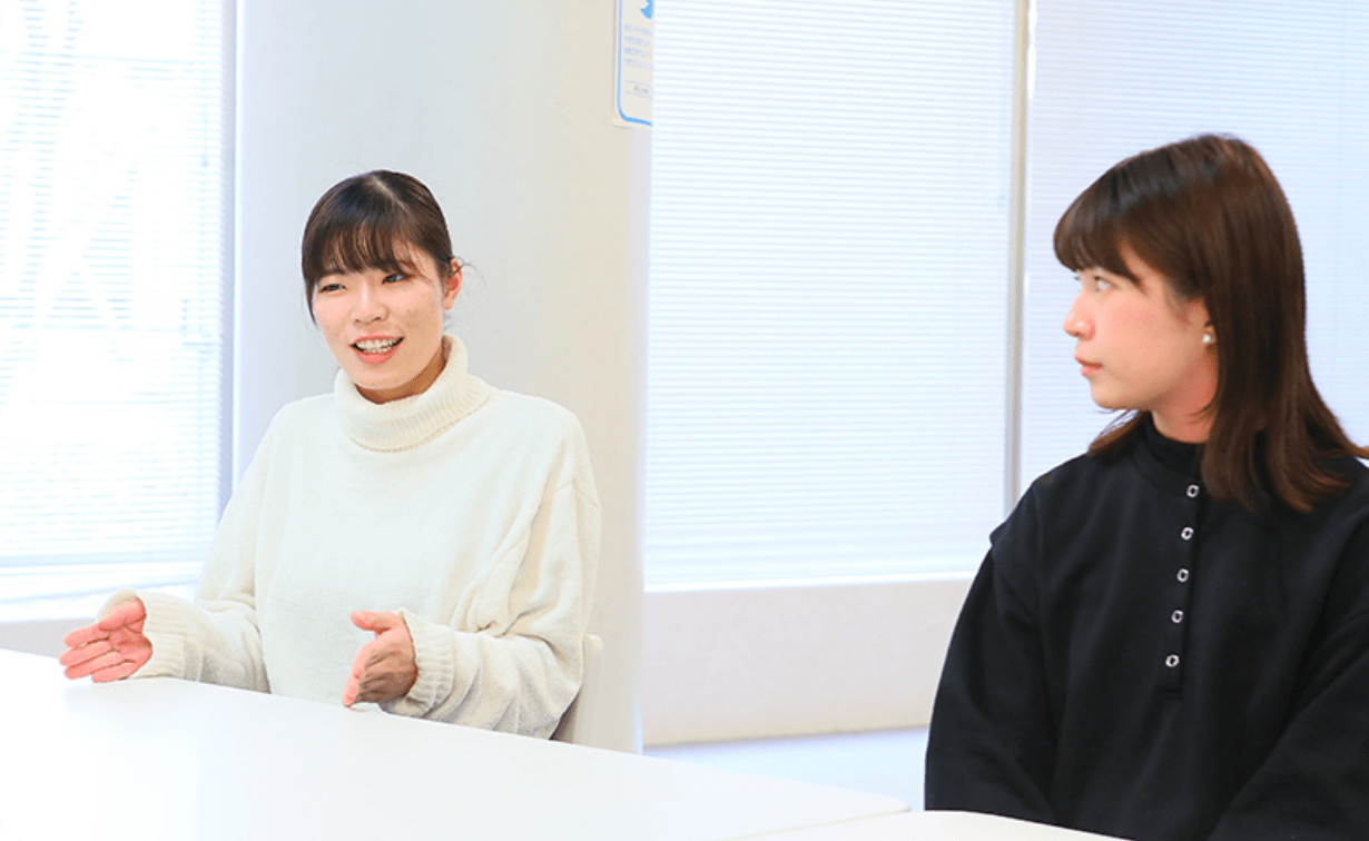 机を挟んで談笑する学生たちの様子