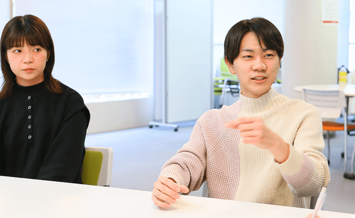 机を挟んで談笑する学生たちの様子